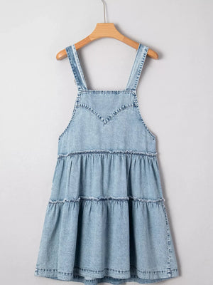 Tiered denim overall dress in light blue with ruffled tiers and V-neck bodice.