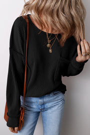 Black ribbed knit long sleeve top with patch pocket and crew neck.