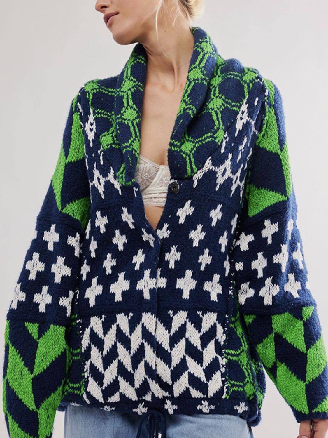 Geometric patchwork knit cardigan in navy, green, and white with a shawl collar and button closure.
