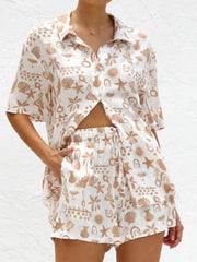 White resort set with tan beach graphic print, button-up shirt and drawstring shorts.