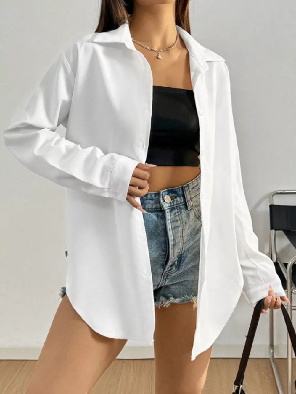 White long sleeve button-up maternity shirt with classic collar, worn open over a black tube top and denim shorts.