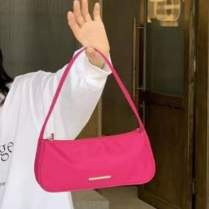 Sleek mini shoulder bag in bright pink nylon with a silver bar detail.