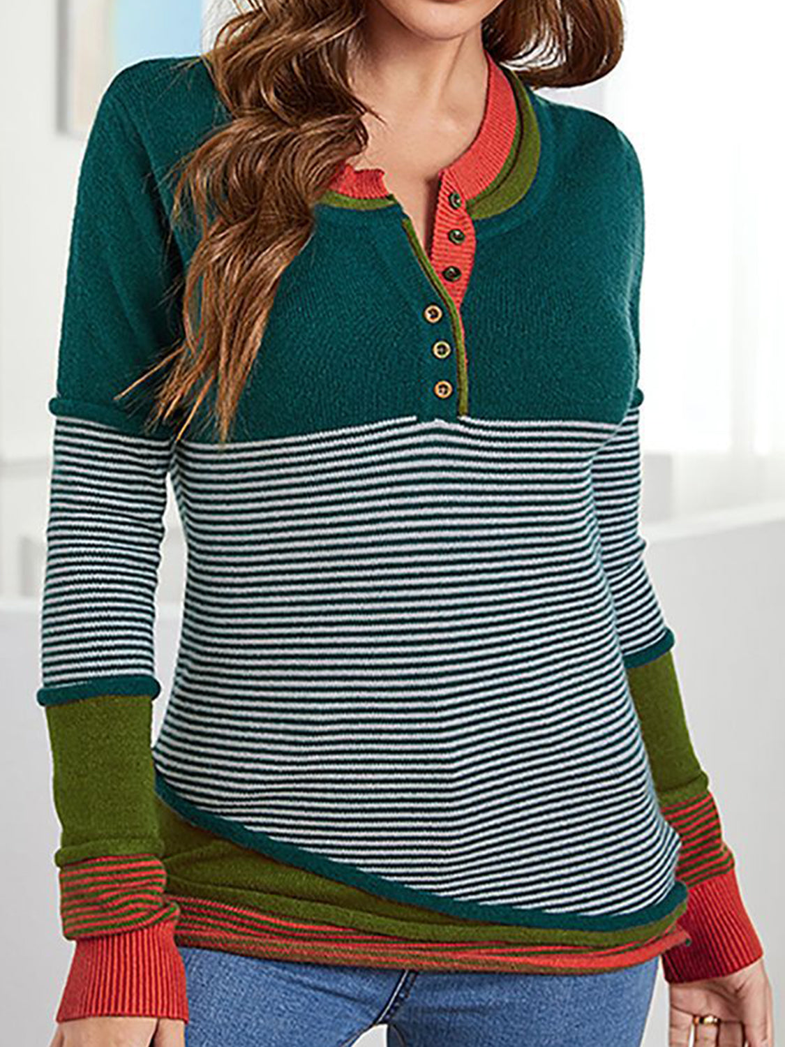 Colorblock henley knit shirt with stripes and button detail. Orange-red trim.