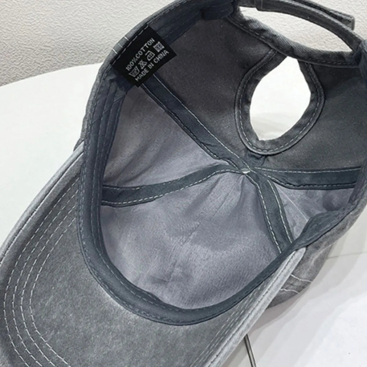Gray cotton baseball cap with ponytail hole and 100% cotton tag.