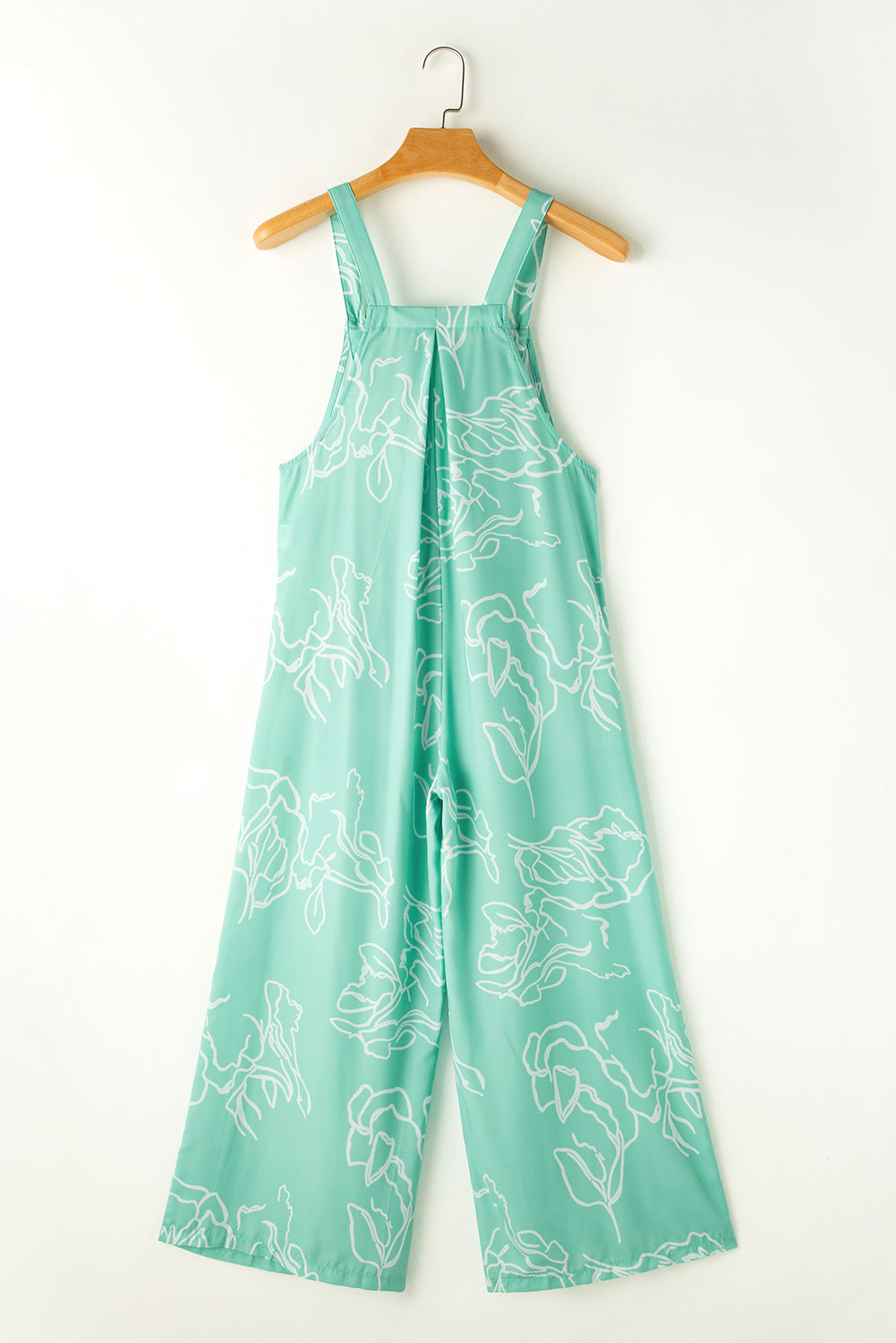 Turquoise botanical print wide-leg jumpsuit with wide straps and pleats.