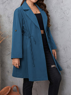 Dusty blue trench coat with gathered waistline, roll-up sleeves, and button closure.