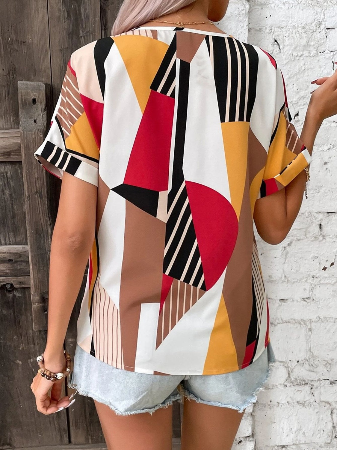 Geometric print V-neck blouse with short sleeves and a multicolor abstract pattern.