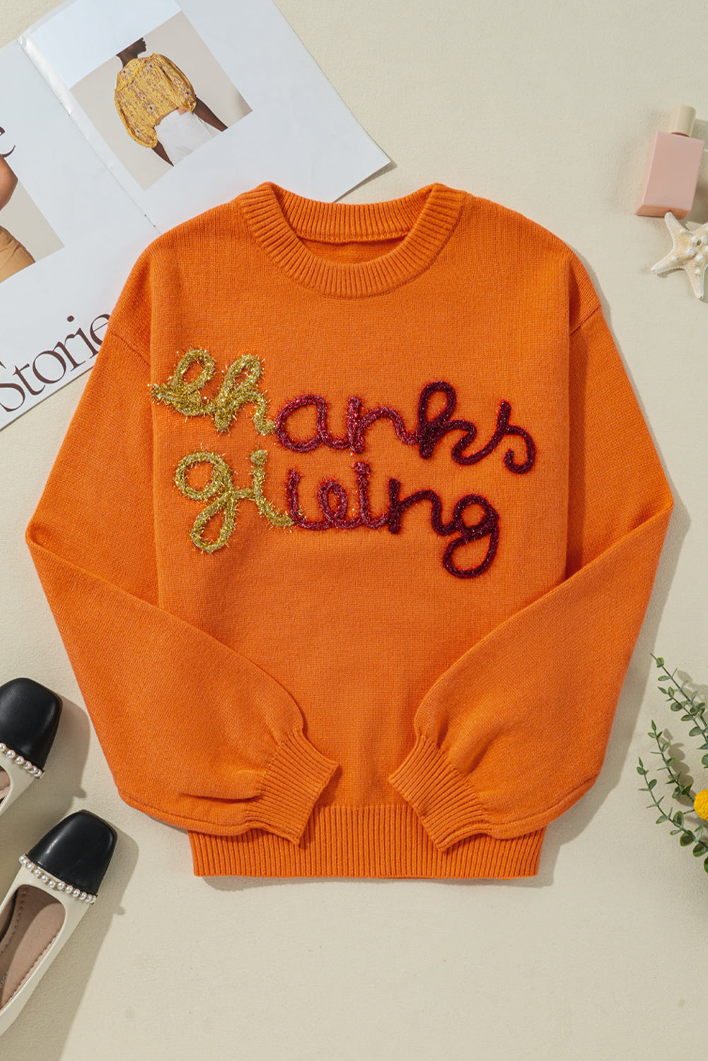 Orange knit sweater with sequin "Thanksgiving" script detail and crew neck.
