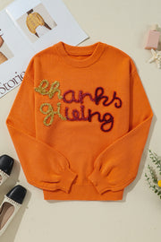Orange knit sweater with sequin "Thanksgiving" script detail and crew neck.