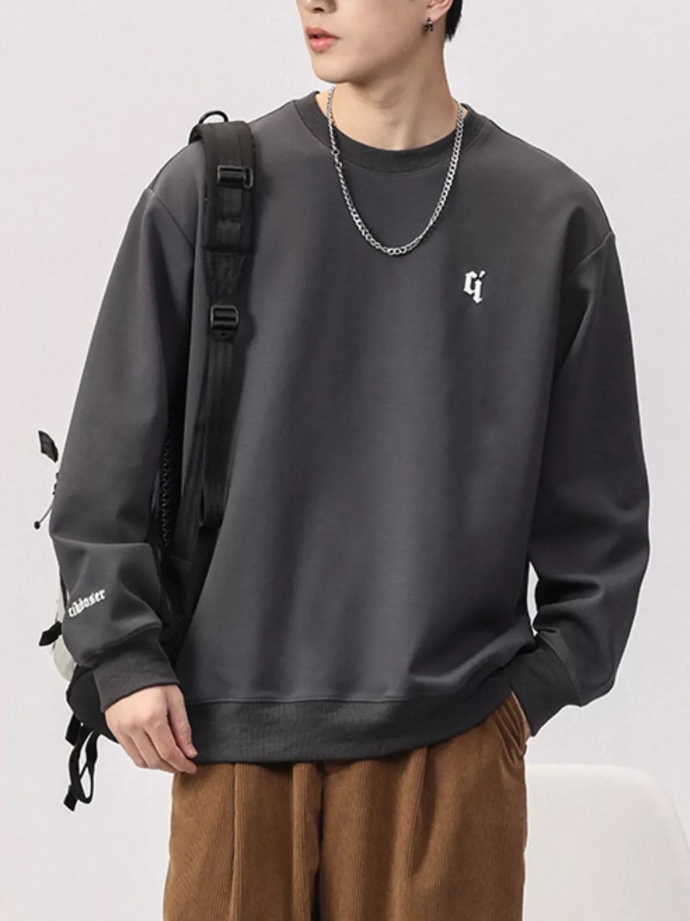 Dark Gray plus-size sweatshirt with round neck, embroidered logo and text detail on sleeve.