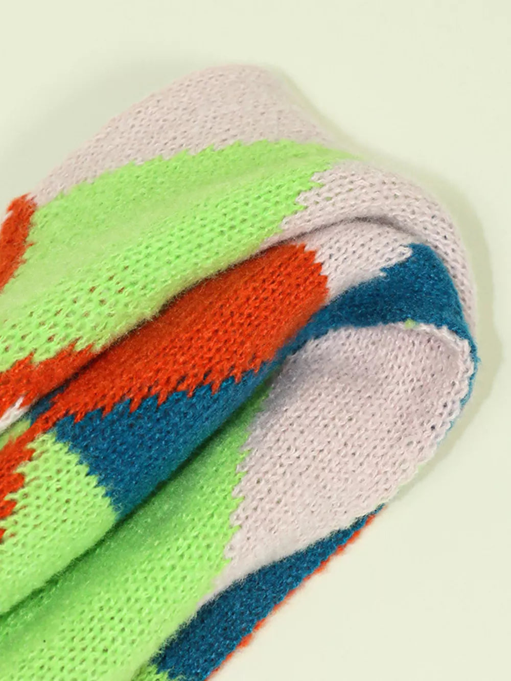 Chunky knit scarf with colorful zigzag stripes in pink, green, orange, and blue.