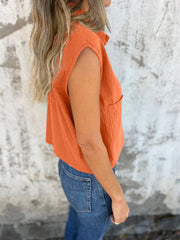 Orange button-down cap sleeve cropped shirt with a pocket.