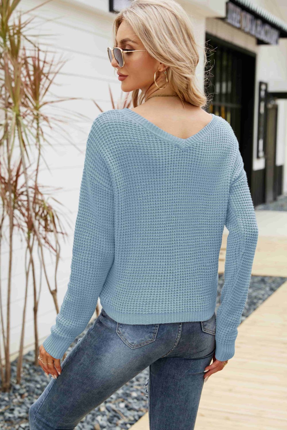 Blue waffle knit sweater with V-neck and long sleeves, styled with jeans.