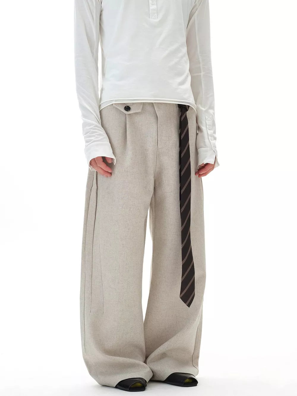 Men's beige wide-leg cargo pants with button closure and striped tie detail.