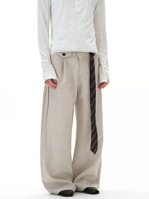 Men's beige wide-leg cargo pants with button closure and striped tie detail.