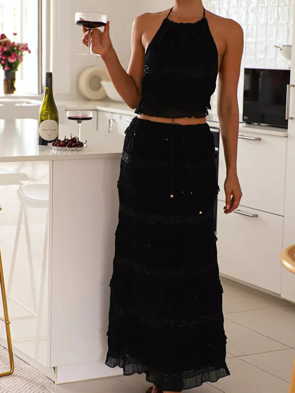 Black halter neck smocked two-piece ensemble with tiered ruffled skirt.