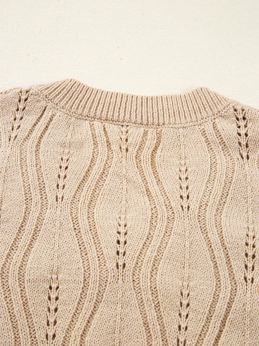 Beige knit sweater with V-neck and cable knit detail.
