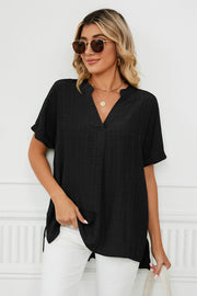 Black linen v-neck blouse with short sleeves and a gathered back detail.