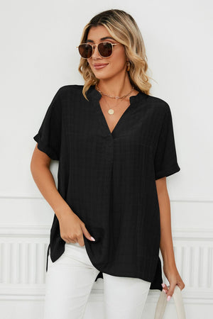 Black linen v-neck blouse with short sleeves and a gathered back detail.