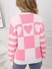 Blush pink and white checkerboard knit sweater with heart details and striped sleeves.