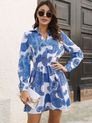 Cobalt blue paisley print shirred waist mini dress with long sleeves and a collared neckline.