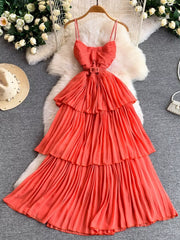 Coral belted pleated midi dress with spaghetti straps and tiered skirt.