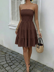 Gathered bodice tiered ruffle mini dress in dark brown, strapless with smocked bust and flowy skirt.