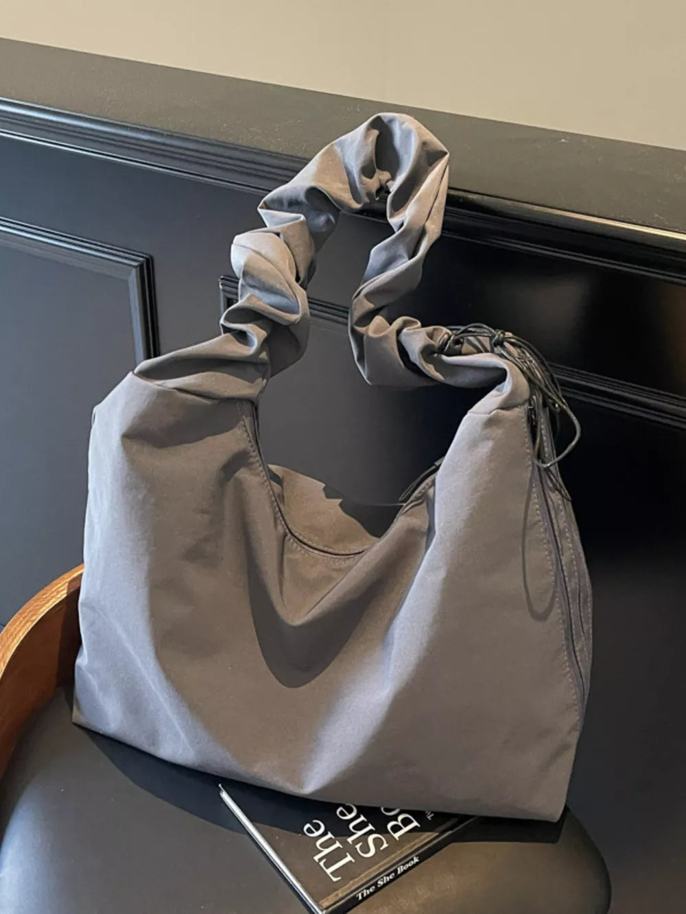 Gray ruched nylon shoulder bag with zipper and decorative tassels.