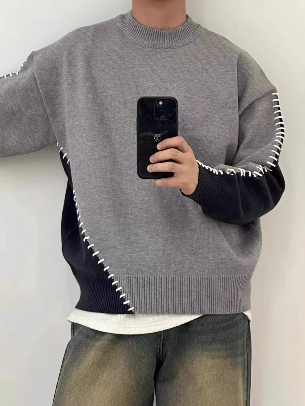 Gray and black two-tone mock neck knit sweater with contrast stitching detail.