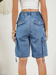 Medium wash denim bermuda shorts with button flap pockets and side cargo pockets.