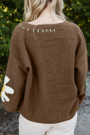 Brown knit sweater with embroidered floral detail on sleeve and neckline.