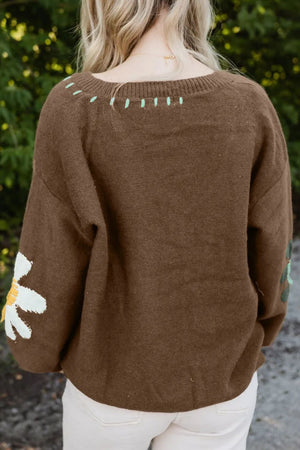 Brown knit sweater with embroidered floral detail on sleeve and neckline.