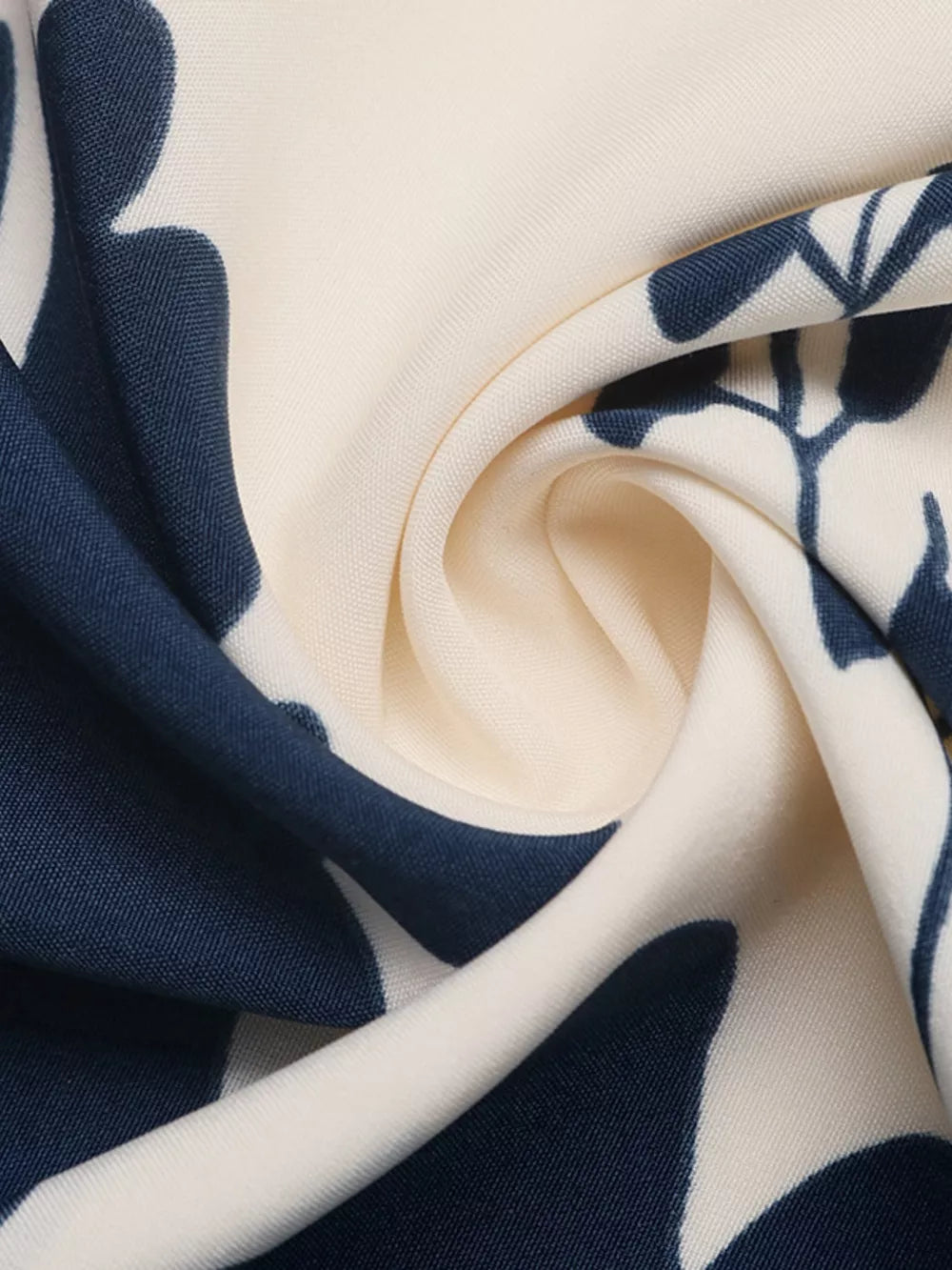 Botanical print maxi dress fabric detail with navy blue leaves on cream.