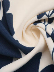 Botanical print maxi dress fabric detail with navy blue leaves on cream.