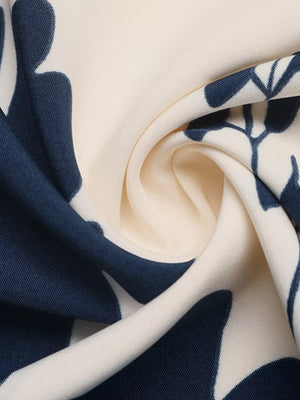 Botanical print maxi dress fabric detail with navy blue leaves on cream.