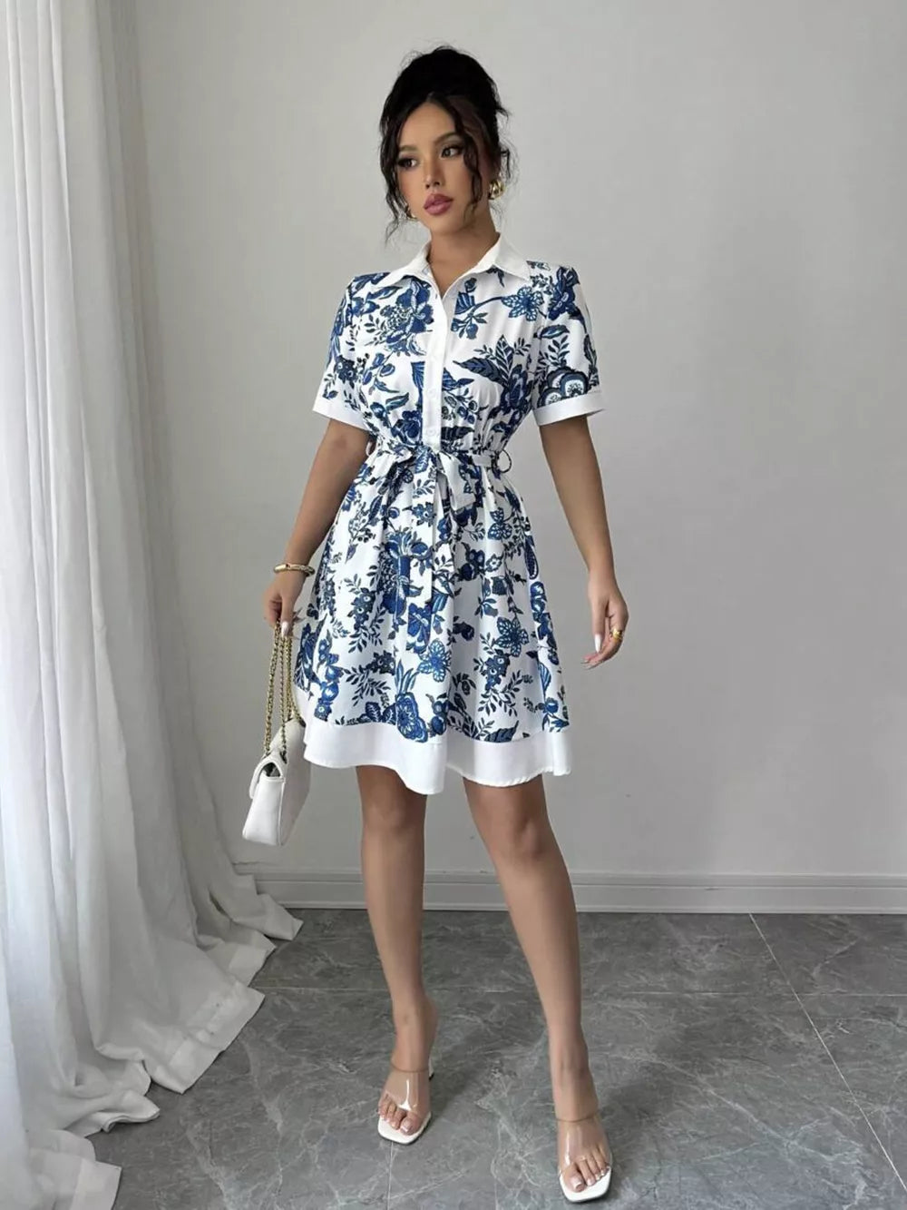 Floral print mini dress in indigo with short sleeves, collared neckline, and tie belt.