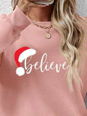 Blush pink raglan sweatshirt with "Believe" graphic and Santa hat detail