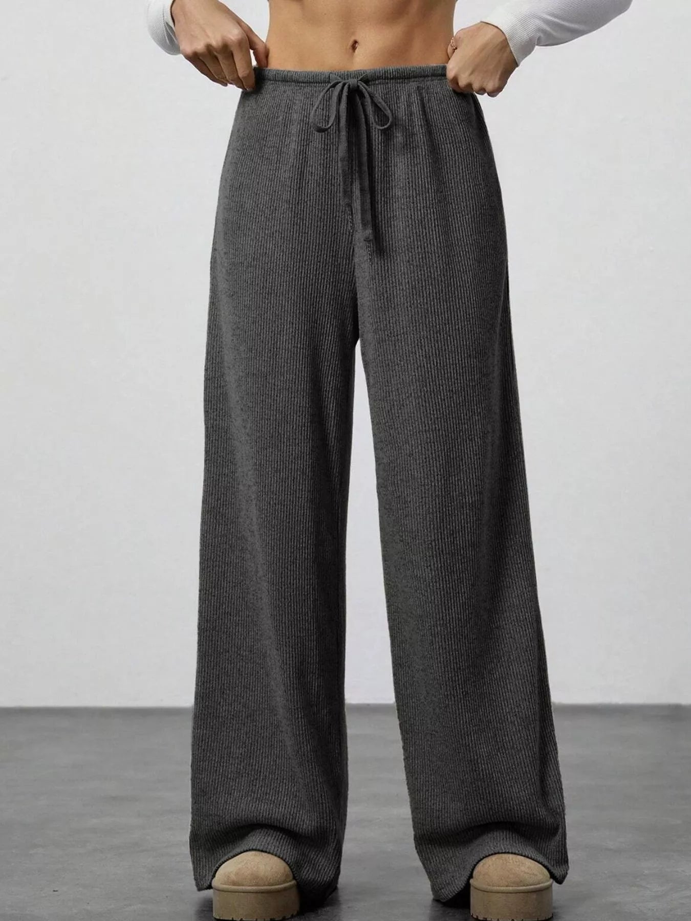 Dark gray ribbed wide-leg pants with drawstring waist and pockets.