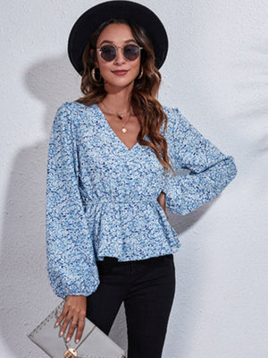 Floral peplum blouse with gathered waist and V-neck in blue and white floral print.
