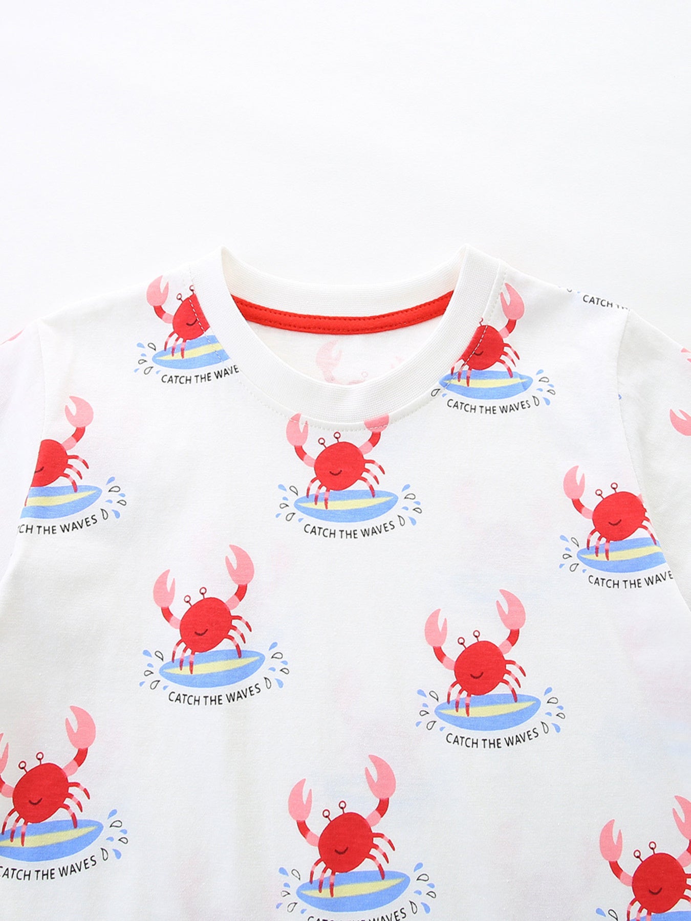 White cotton toddler t-shirt with all-over red surfing crab print and red neckline trim.