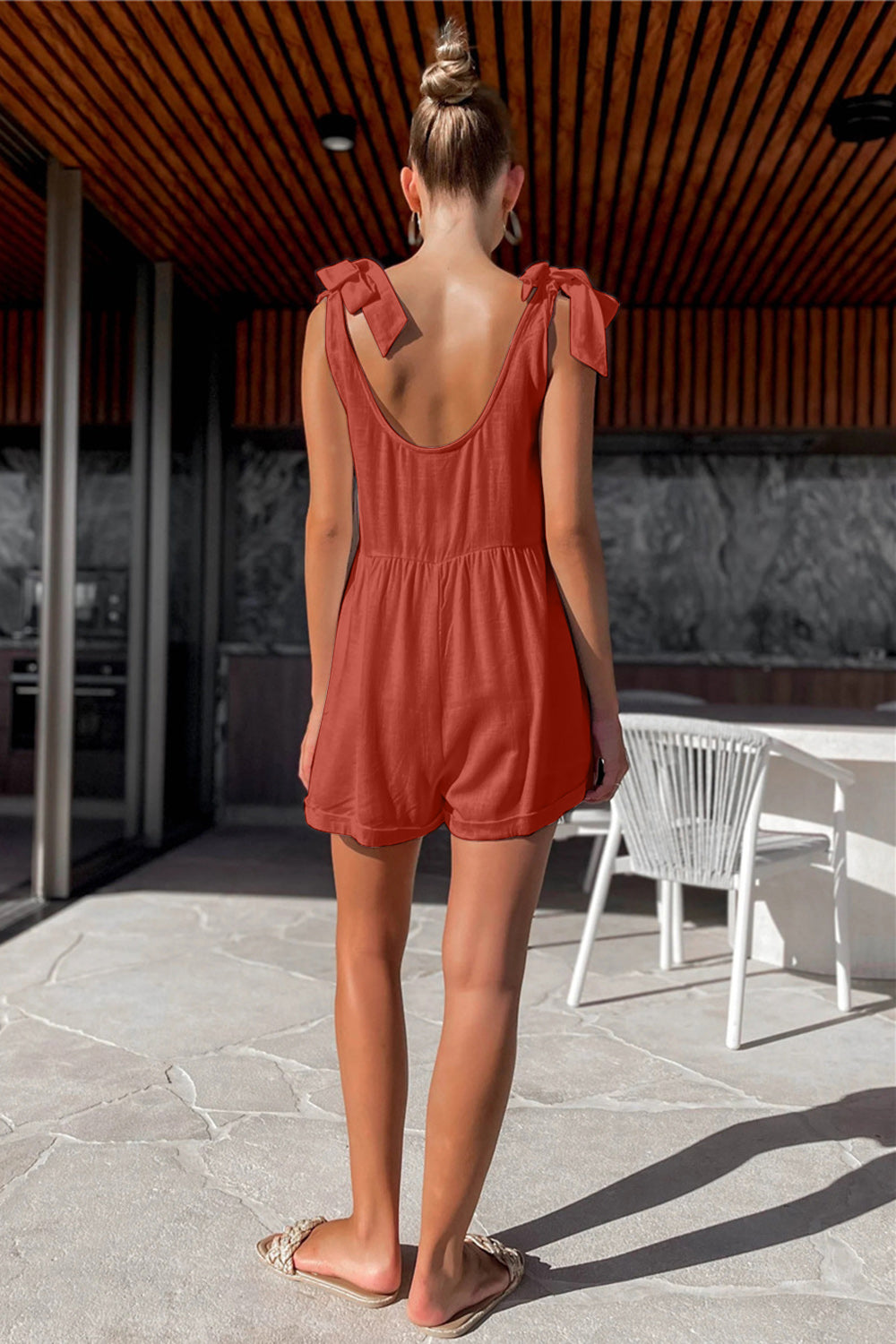 Gathered waist romper with bow shoulder straps in a burnt orange color.