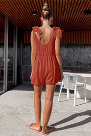 Gathered waist romper with bow shoulder straps in a burnt orange color.