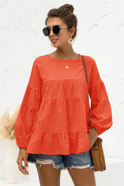 Orange tiered peasant blouse with ruffled balloon sleeves and crew neck.