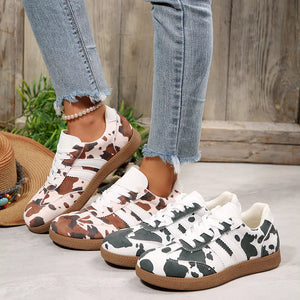 Trendy cow print low-top sneakers in brown and black with white stripes and gum soles.