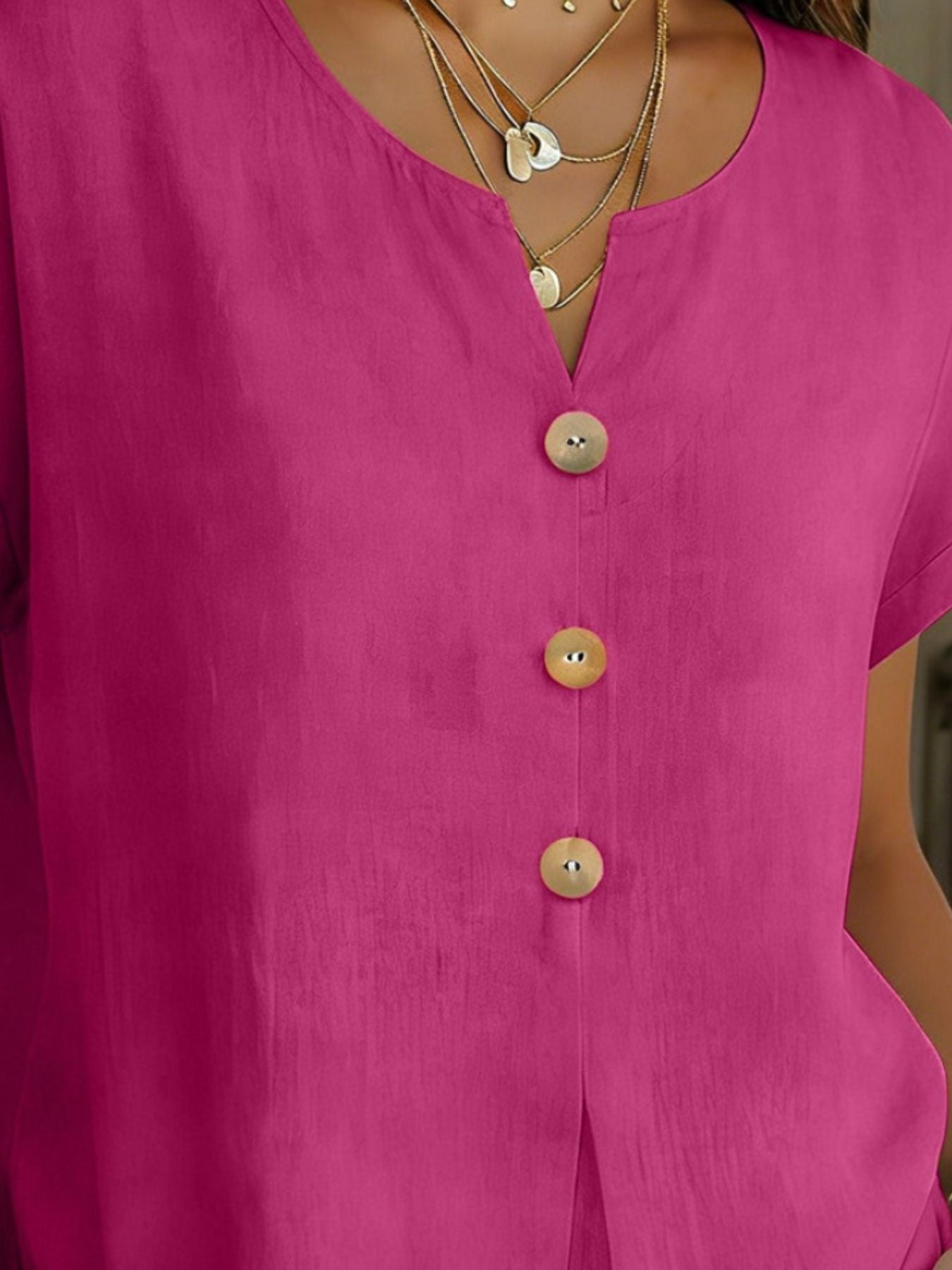 Buttoned short sleeve blouse in cerise with a V-neck and wooden buttons.
