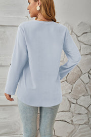 Light blue V-neck button-down blouse with cuffed long sleeves and a curved hem.