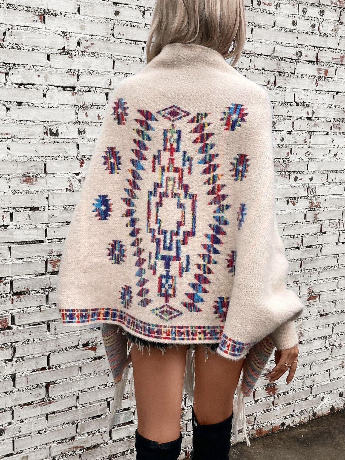 Cream Aztec fringe knit cardigan with colorful geometric pattern and fringe detail.