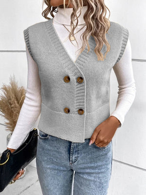 Gray double-breasted knit vest with ribbed trim and button closure, worn over a white turtleneck.