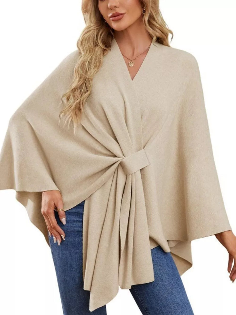 Beige knit cape top with V-neck and tie-front detail, draped elegance.