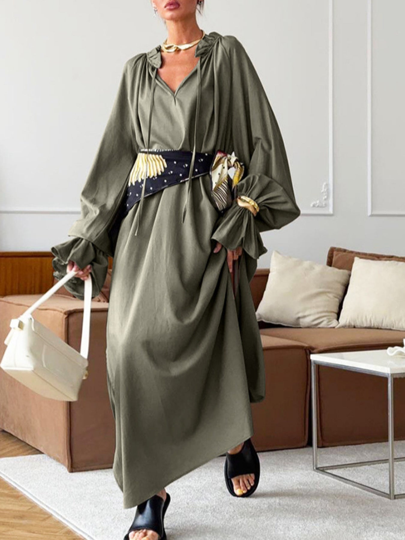 Army green cotton maxi dress with tie neck and ruffled sleeves, styled with a patterned belt.